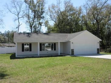 Charming single-story home boasts a well-manicured lawn, attached two-car garage, and a welcoming front porch at 13024 Ne 6 Pl, Silver Springs, FL 34488