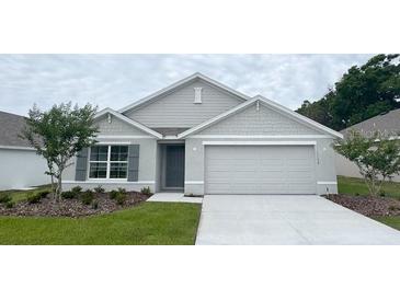 Charming single-story home featuring a gray color scheme, two-car garage, and a well-manicured lawn at 11152 Se 68Th Ct, Belleview, FL 34420