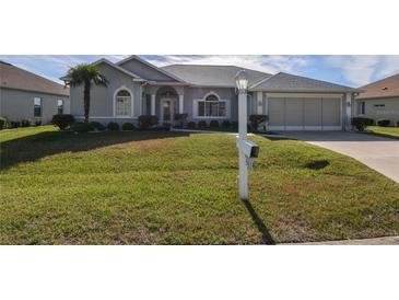 Single-story home with gray siding, two-car garage, and a well-manicured lawn at 5622 Nw 27Th Pl, Ocala, FL 34482