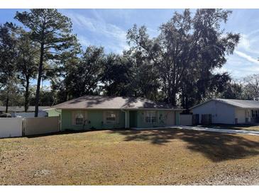 Green house with brown roof, white fence, and large yard at 35 Hemlock Terrace Dr, Ocala, FL 34472