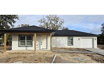 Newly constructed home featuring a charming front porch, a one car garage, and fresh landscaping at 519 Sw 19Th Ave, Ocala, FL 34471