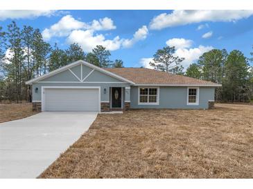 Newly constructed home with light blue exterior, attached garage, and driveway at 8436 Sw 136Th Ter, Dunnellon, FL 34432