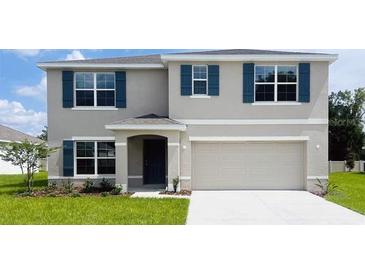 Two-story home featuring blue shutters, a manicured lawn, and a two-car garage at 9989 Se 161St Lane Rd, Summerfield, FL 34491