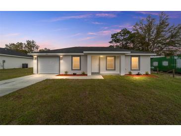 Charming single-story home featuring a freshly painted facade, landscaped front yard, and an attached garage at 13559 Sw 115 Pl, Dunnellon, FL 34432