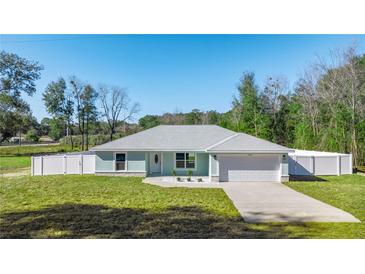 Newly built home with light teal exterior, white fence, and a two-car garage at 14462 Se 28Th Ct, Summerfield, FL 34491