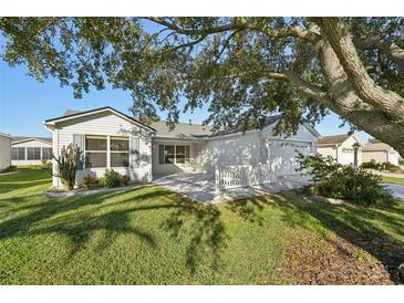 Charming home featuring a well-manicured lawn and an inviting patio area, perfect for outdoor living at 2427 Due West Dr, The Villages, FL 32162