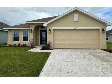 Inviting single-story home with a neutral-colored facade, well-manicured lawn, and attached two-car garage at 4477 Sw 90Th Pl, Ocala, FL 34476
