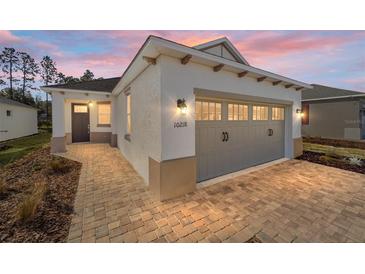 Craftsman style home with gray garage door and paver driveway at 10218 Sw 99Th Ln, Ocala, FL 34481