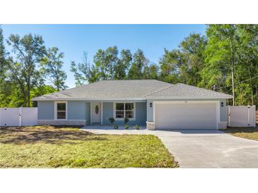 Newly constructed home with light blue exterior, white fence, and attached garage at 28 Pecan Run, Ocala, FL 34472