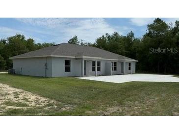 An exterior view showing the back of the house with a lawn and a concrete slab patio at 5489 Nw 12Th. St, Ocala, FL 34482