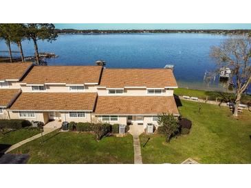 Waterfront condo complex featuring well-maintained landscaping and private docks on a sunny day at 11001 Se Sunset Harbor Rd # B10, Summerfield, FL 34491