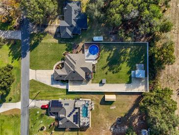 An aerial view of a well-maintained home with a swimming pool and expansive green lawn at 36323 Piney Ridge Blvd, Fruitland Park, FL 34731