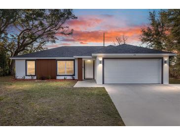 Charming single-story home featuring a two-car garage, modern wood paneling, fresh landscaping, and a welcoming facade at 4393 Sw 169 Lane Rd, Ocala, FL 34473