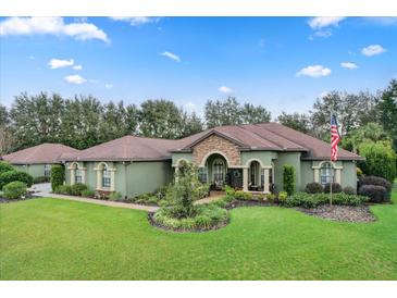 Green house with brown roof and landscaping, American flag visible at 7451 Se 24Th Ter, Ocala, FL 34480