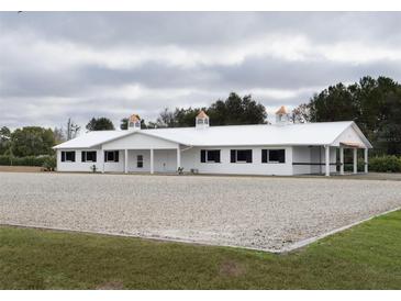 White horse barn with cupola and black window accents at 2190 Nw 110Th Ave, Ocala, FL 34482
