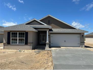 Charming single-story home with a gray roof, a two-car garage, and stucco siding, set against a bright blue sky at 3154 Ne 46Th Ave, Ocala, FL 34470