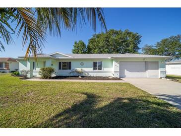 Charming single-story home with a well-maintained lawn, two-car garage, and lush landscaping at 6184 Sw 101St Pl, Ocala, FL 34476