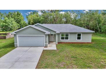 Charming single-story home featuring a light-gray exterior, attached garage, and well-maintained lawn at 963 Nw 65Th St, Ocala, FL 34475