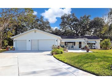 White Ranch house with two-car garage, awning, and landscaped lawn at 10185 Se 175Th Ln, Summerfield, FL 34491