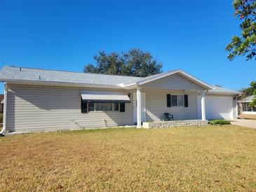 Tan single story home with attached garage, covered porch and a low retaining wall at 10736 Sw 62Nd Ave, Ocala, FL 34476