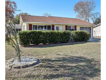 Single story home with yellow siding, red shutters, and manicured lawn at 10962 Sw 80 Ct, Ocala, FL 34481