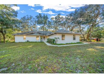 Single story home with a spacious yard, walkway and mature trees at 14221 Ne 47Th Ave, Anthony, FL 32617