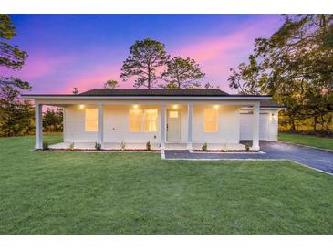 White house with front porch, driveway, and landscaped lawn at 15002 Sw 27 St, Ocala, FL 34481