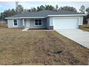 Newly constructed home with gray siding, white garage door, and a small front yard at 5 Locust Trak, Ocala, FL 34472