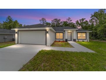 Beautiful single-story home featuring a two-car garage, manicured lawn, and a welcoming entryway at twilight at 55 Locust Loop Cir, Ocala, FL 34472