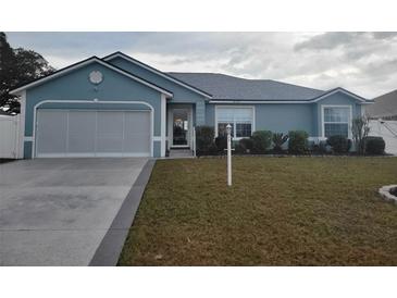 One-story home with gray siding, a two-car garage, and well-manicured lawn at 8187 Sw 60Th Ter, Ocala, FL 34476