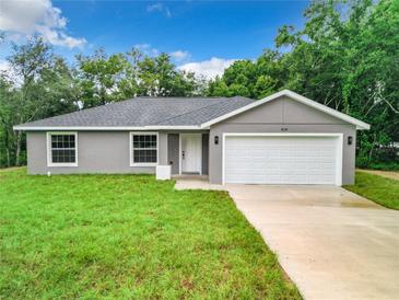 Gray house with white garage door and green lawn at 4482 Sw Clearwater Ct, Dunnellon, FL 34431