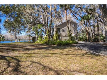 Two-story house with lake view, surrounded by lush trees and landscaping at 4925 Cr 309B, Lake Panasoffkee, FL 33538