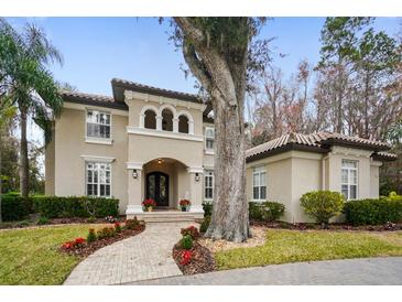 Two-story house with a tile roof, arched entryway and landscaped yard at 1219 Se 46Th St, Ocala, FL 34480