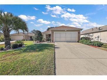 Single-story house with attached garage, and a well-manicured lawn at 12498 Se 92Nd Ave, Summerfield, FL 34491