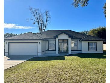 A newly constructed home with a white exterior, dark accents, and a well-manicured lawn at 1846 Ne 127Th Pl, Anthony, FL 32617