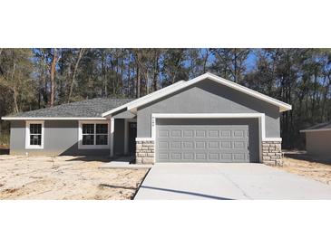 Newly constructed home with gray exterior, stone accents, and a two-car garage at 46 Locust Pass Run, Ocala, FL 34480