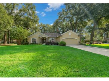 One-story house with a large front yard, driveway, and mature trees at 4977 Se 44Th Cir, Ocala, FL 34480