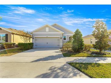 Two-story house with a gray exterior, two-car garage, and landscaping at 5325 Sunshine Dr, Wildwood, FL 34785