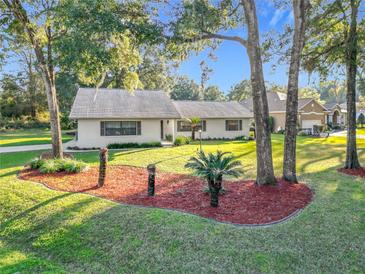 Ranch home with landscaped yard, featuring red mulch beds and mature trees at 9050 Sw 190Th Cir, Dunnellon, FL 34432