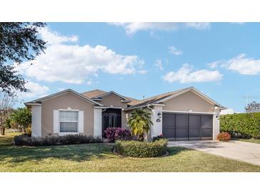 Tan one-story house with a three-car garage and manicured landscaping at 15692 Sw 11Th Court Rd, Ocala, FL 34473