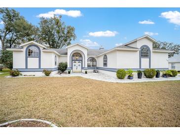 Charming single-story home with white exterior, blue trim, landscaped yard, and arched windows at 7528 Sw 102Nd Loop, Ocala, FL 34476