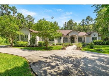 Stately stucco home with a circular driveway, mature trees, and professionally landscaped front yard at 995 Sw 37Th Place Rd, Ocala, FL 34471