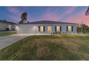 Gray house with a gray garage door, blue shutters, and a well-manicured lawn at 13198 Sw 29Th Cir, Ocala, FL 34473