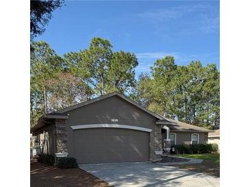 House exterior featuring a two-car garage and a well-manicured lawn at 3 Maple Run, Ocala, FL 34472