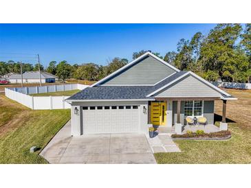 Gray house with yellow door, two-car garage, and landscaped yard at 4709 Se 25Th Loop, Ocala, FL 34480