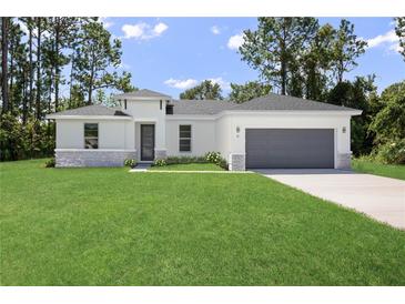 White house with gray garage door and stone accents at 5096 Sw 154Th Loop, Ocala, FL 34473