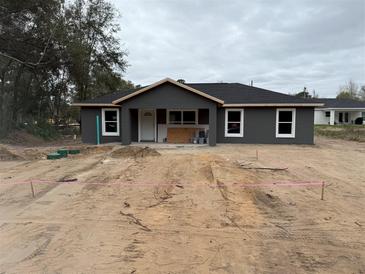 New construction home with gray siding, a black roof, and white trim ready for landscaping at 5411 Nw 7Th Pl, Ocala, FL 34482