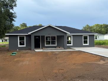 Charming single-story home featuring a modern gray exterior, black roof, and a well-manicured front yard ready for landscaping at 5411 Nw 7Th Pl, Ocala, FL 34482