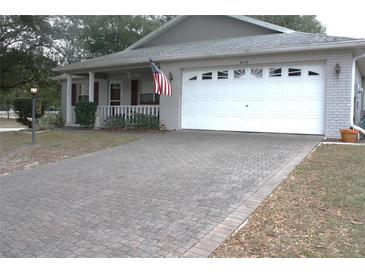 Brick ranch home with a large white garage door and paver driveway at 9662 Sw 97Th Ln, Ocala, FL 34481