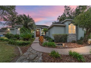 Beautiful home with landscaped walkway, lush greenery, and a pond feature at dusk at 1105 Se 48Th Ave, Ocala, FL 34471